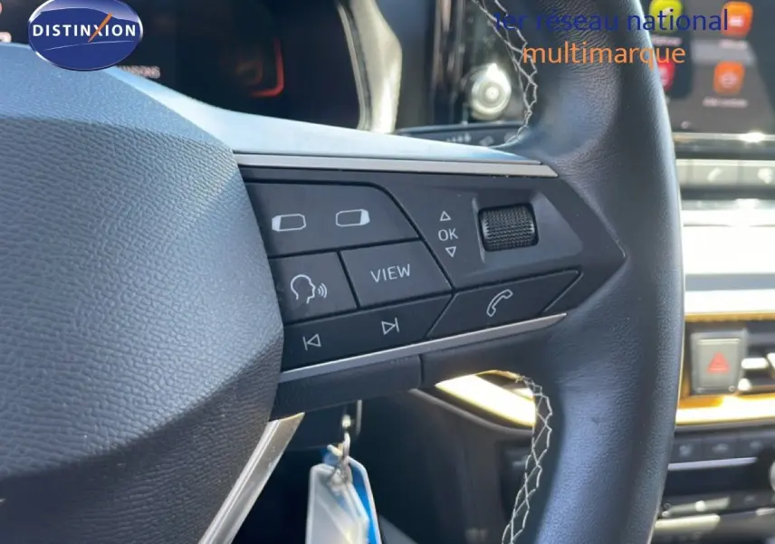 Gros plan sur le volant en cuir noir avec commandes multifonctions du SEAT Arona gris Magnetic Metal, intérieur moderne.