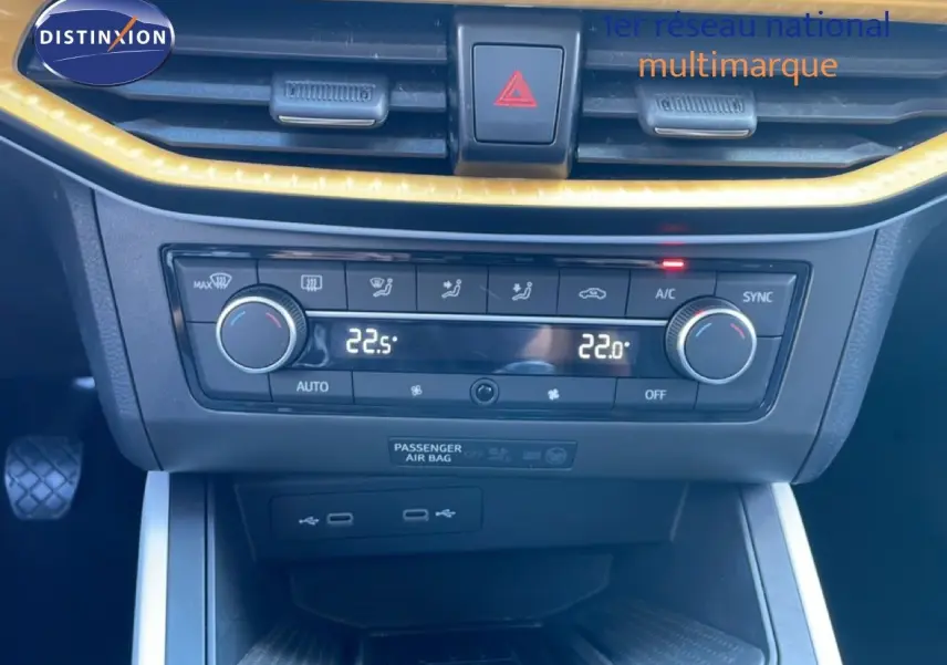 Gros plan sur la console centrale du SEAT Arona 2025, montrant la climatisation digitale et les commandes en noir avec contour jaune.