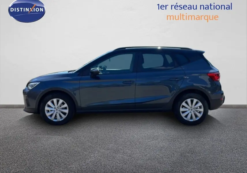 Vue de profil côté gauche d'un SEAT Arona gris Magnetic Metal avec toit noir, en arrière-plan un mur blanc.