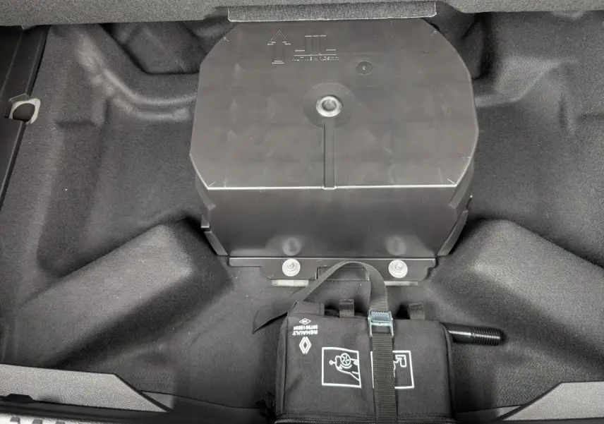 Vue rapprochée du coffre du Renault Austral gris, montrant le rangement sous plancher avec trousse à outils attachée.