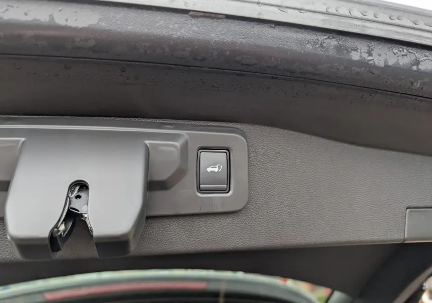 Gros plan sur le bouton d'ouverture électrique du hayon du Renault Austral gris, vu depuis l'intérieur du coffre.