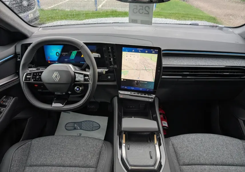 Vue intérieure avant du Renault Austral 2025 gris, avec tableau de bord numérique et écran tactile central vertical.