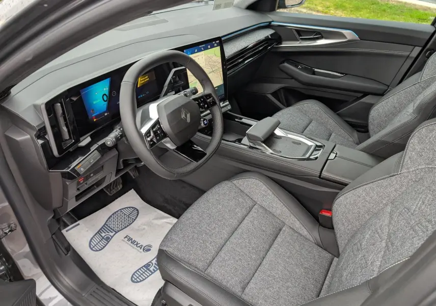 Vue intérieure côté conducteur du Renault Austral gris, avec tableau de bord numérique et sellerie tissu gris clair.