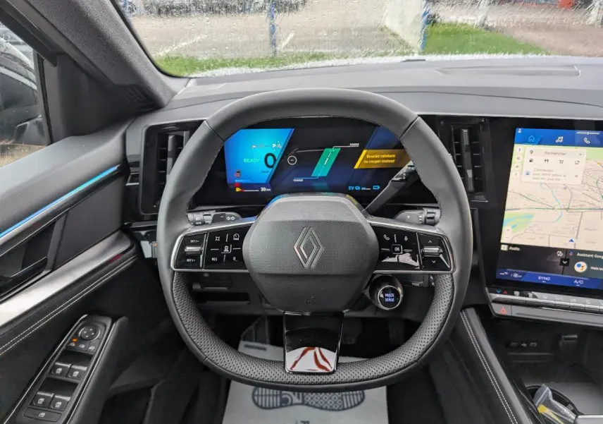 Vue intérieure centrée sur le volant noir du Renault Austral 2025 avec tableau de bord numérique et écran tactile latéral.
