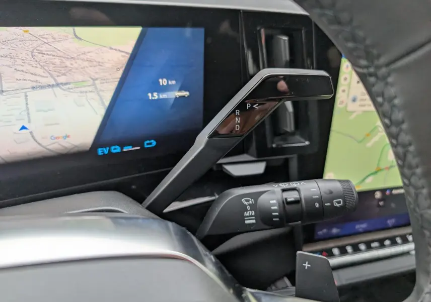 Gros plan intérieur sur la commande de boîte automatique et l’écran numérique du Renault Austral gris, affichant la navigation.