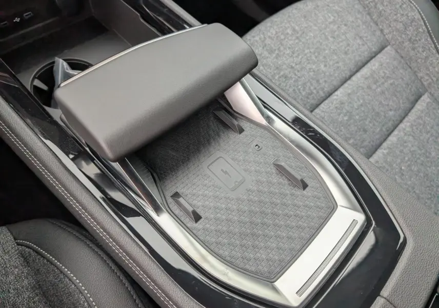 Gros plan sur la console centrale noire avec chargeur smartphone à induction et accoudoir gris du Renault Austral 2025.