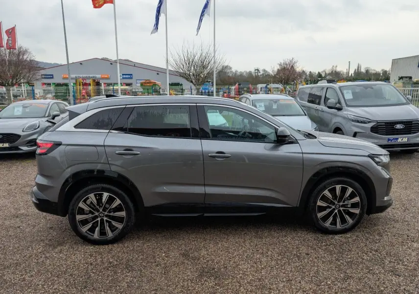 Vue de profil droit du Renault Austral gris avec jantes alliage noires diamantées sur un parking extérieur.