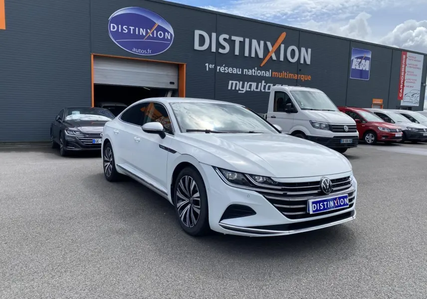 Volkswagen Arteon blanc pur en 3/4 avant droit, avec jantes alliage et calandre chromée visible.