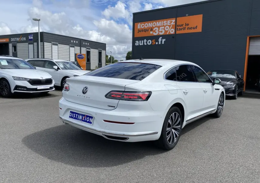 Volkswagen Arteon blanc pur vue 3/4 arrière droit avec jantes alliage et vitres teintées sur parking.