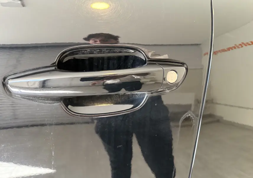 Poignée de porte noire brillante du Citroën C5 Aircross 2022, reflet d'une personne visible sur la carrosserie.