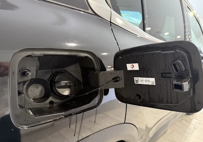 Gros plan sur la trappe à carburant ouverte du Citroën C5 Aircross gris Artense, montrant le bouchon et les étiquettes E5 et E10.