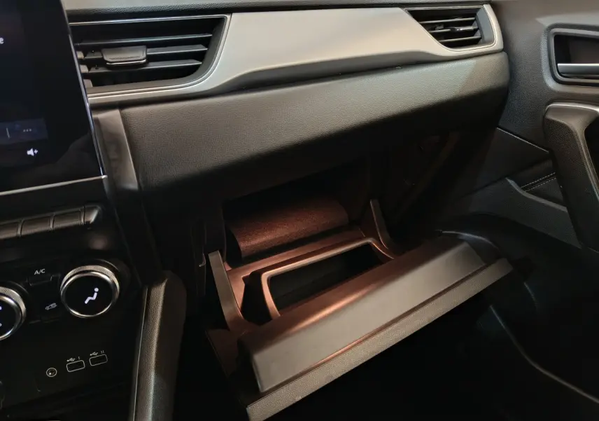 Intérieur du Renault Captur 2024 gris foncé, vue côté passager sur la boîte à gants ouverte et la console centrale.