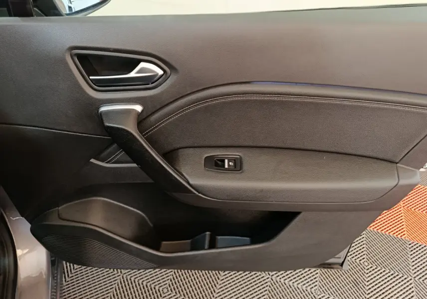 Vue intérieure côté gauche de la porte avant gris foncé du Renault Captur 2024 avec poignée et commande de vitre.