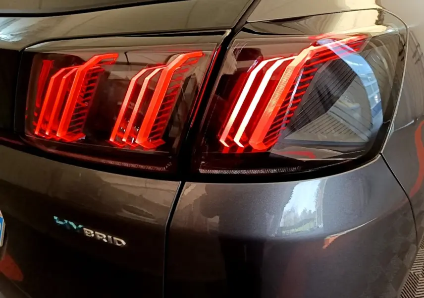 Gros plan sur les feux arrière allumés côté droit d’un Peugeot 3008 gris foncé hybride rechargeable.
