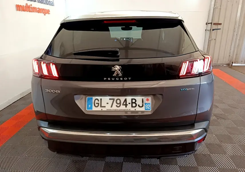 Vue arrière d'un Peugeot 3008 gris foncé hybride avec feux LED caractéristiques allumés en intérieur.