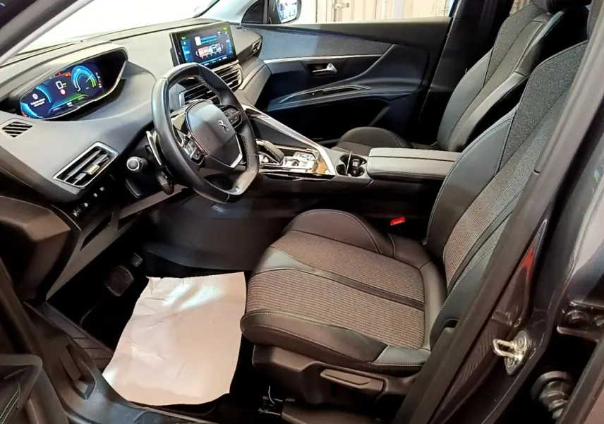 Vue intérieure côté conducteur du Peugeot 3008 gris foncé, avec tableau de bord digital et sièges tissu-cuir noirs.