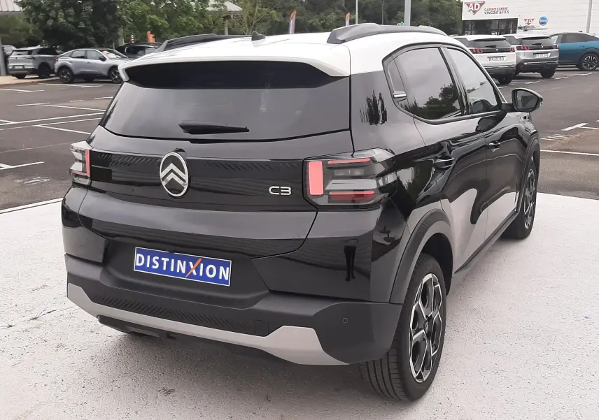 Vue 3/4 arrière droite d'une Citroën C3 2025 noir perla avec toit blanc, feux arrière LED et jantes bi-ton.