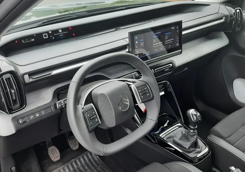 Vue intérieure côté conducteur de la Citroën C3 2025 avec volant multifonctions, écran tactile et levier de vitesses manuel.