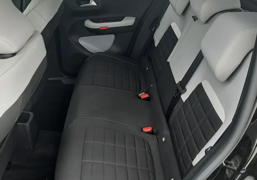 Vue intérieure arrière côté droit de la Citroën C3 2025, sièges bicolores noir et blanc avec tissu matelassé.
