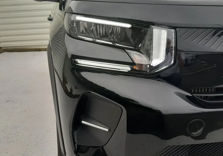 Gros plan sur l'avant gauche noir perla avec toit blanc de la Citroën C3 2025, mettant en valeur les phares LED distinctifs.