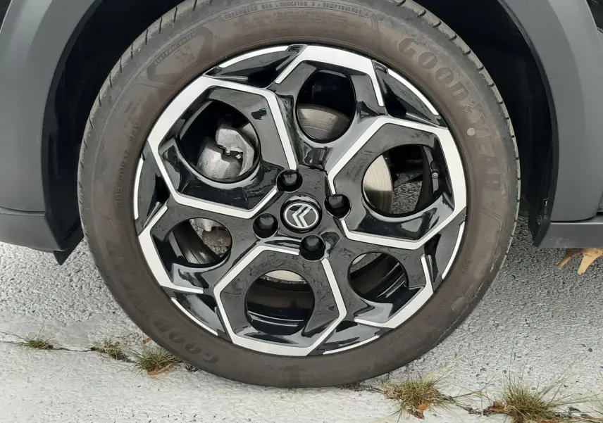 Gros plan sur la roue avant gauche d'une Citroën C3 2025 noir perla avec jante alliage noire et argentée au design hexagonal.