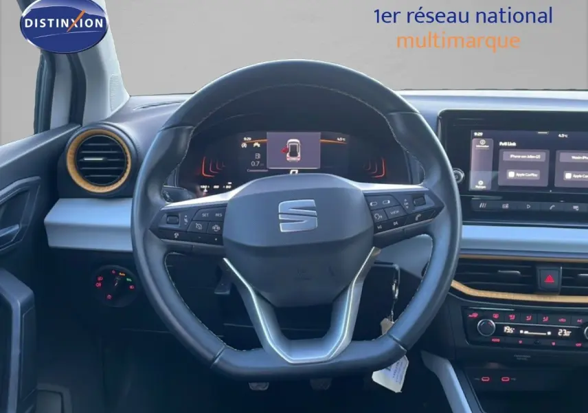 Vue intérieure centrée sur le volant cuir du SEAT Arona 2025, tableau de bord numérique et écran tactile visibles.