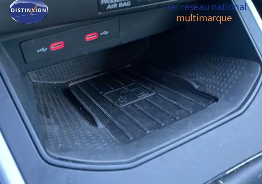 Gros plan sur la console centrale avec deux ports USB rouges et un espace de recharge sans fil dans un SEAT Arona blanc toit gris.