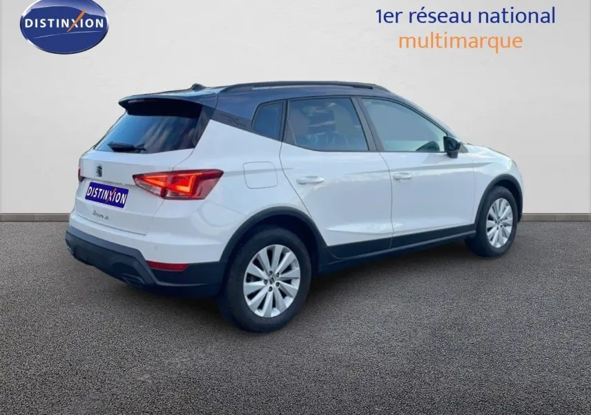 Vue 3/4 arrière côté droit d’un SEAT Arona blanc avec toit gris, jantes alliage et feux arrière LED.