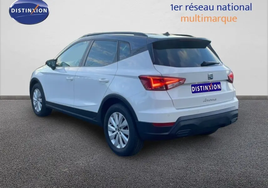 Vue 3/4 arrière droite d'un SEAT Arona blanc avec toit gris, feux arrière allumés et jantes alliage.
