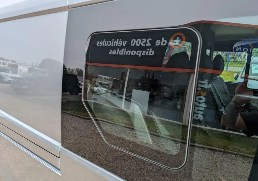Vue latérale gauche rapprochée du Renault Trafic Fourgon gris Highland, mettant en valeur la vitre ouvrante coulissante.