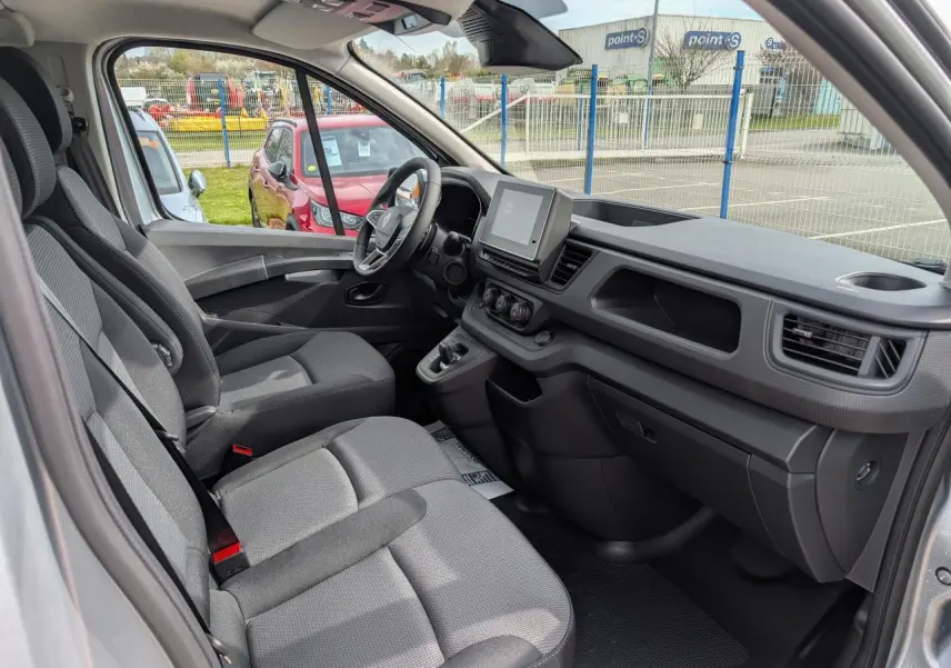 Vue intérieure côté conducteur du Renault Trafic Fourgon gris, mettant en valeur la cabine approfondie et l'écran tactile central.