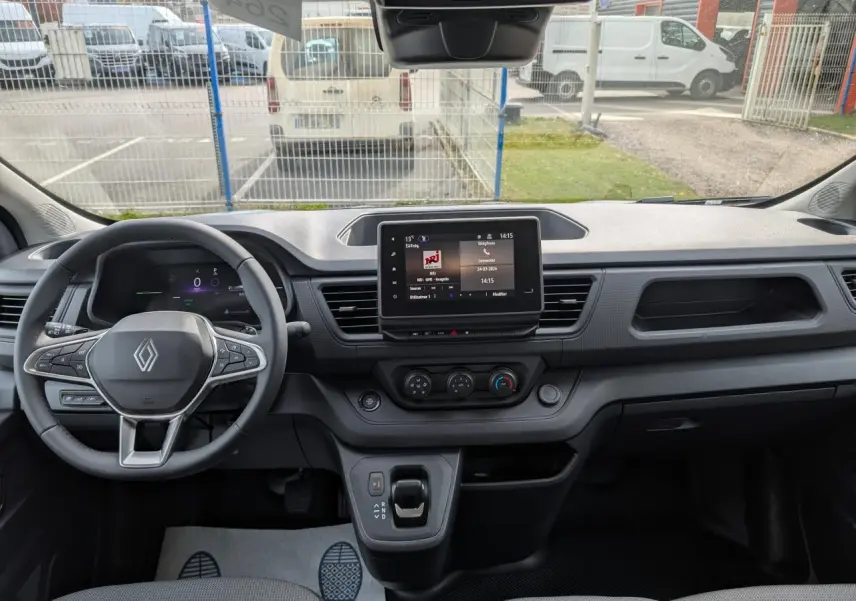 Vue frontale de l'intérieur gris du Renault Trafic Fourgon 2025, avec tableau de bord numérique et écran tactile central.