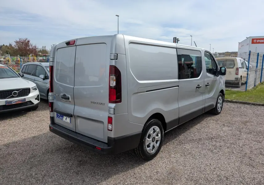 Renault Trafic Fourgon gris Highland vu en 3/4 arrière droit, avec portes arrière tôlées et enjoliveurs 16 pouces.