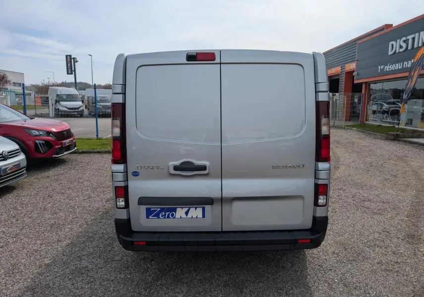 Vue arrière d'un Renault Trafic Fourgon gris avec portes battantes et feux arrière intégrés à la carrosserie.