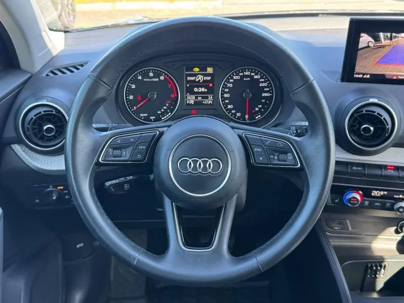 Vue centrée sur le volant cuir de l'Audi Q2 35 TFSI S line 2023 avec tableau de bord et écran multimédia visible.