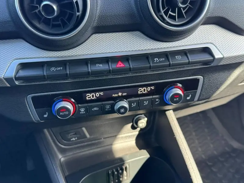 Tableau de bord de l'Audi Q2 35 TFSI 150ch S line 2023, vue centrale sur la climatisation digitale et les aérateurs ronds noirs.