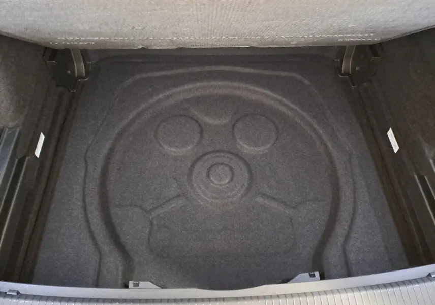 Vue plongeante sur le coffre vide du Volkswagen Tiguan 2.0 TDI 150 DSG7 R-Line, avec espace de rangement en moquette noire.