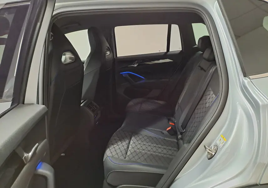 Vue intérieure côté gauche des sièges arrière en cuir noir avec surpiqûres et éclairage d'ambiance bleu du Volkswagen Tiguan 2025 argent Dolomite.