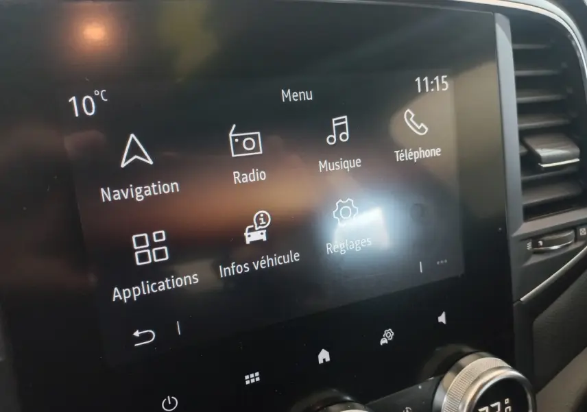 Écran tactile central de la Renault Mégane Business gris foncé, affichant menu navigation, radio et réglages.