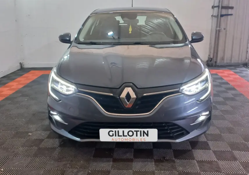 Vue frontale d'une Renault Mégane Business TCe 115 gris foncé avec phares LED allumés dans un garage.
