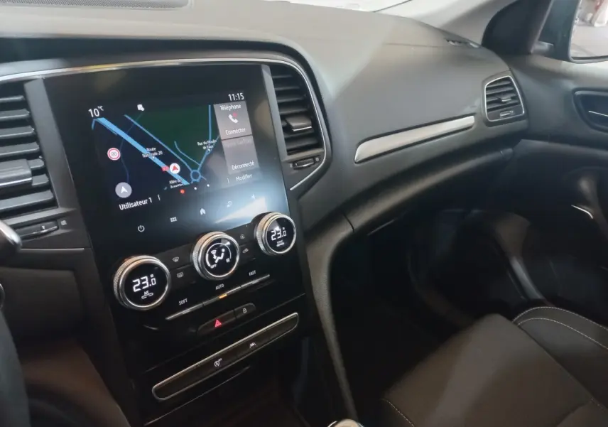 Vue intérieure côté passager de la Renault Mégane Business 2022, avec écran tactile et commandes de climatisation visibles.