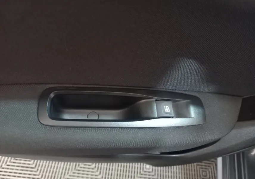 Gros plan sur la commande de lève-vitre côté droit de la porte intérieure d'une Renault Mégane Business gris foncé.