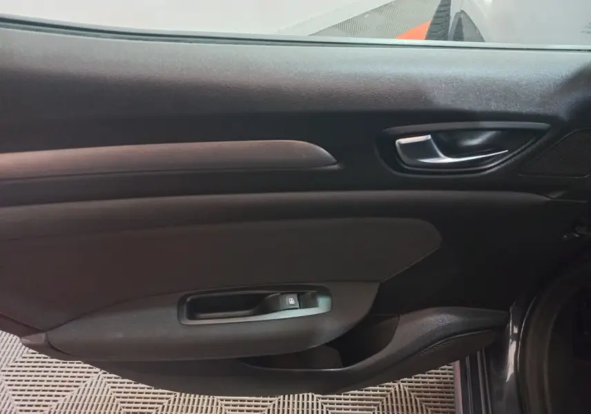 Vue intérieure côté droit de la porte avant gris foncé de la Renault Mégane Business TCe 115 FAP 2022 avec poignée et commande de vitre.