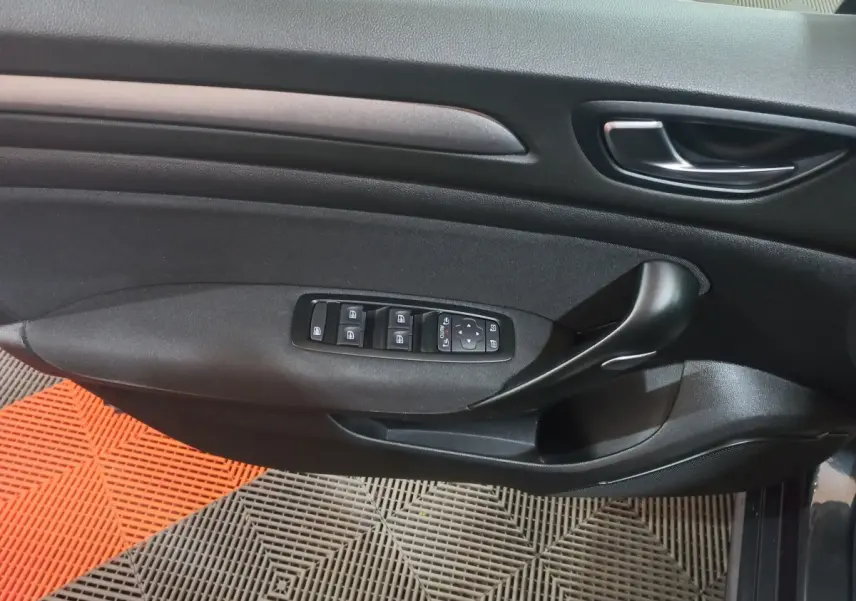 Vue rapprochée de la porte côté gauche de la Renault Mégane Business gris foncé, avec commandes électriques des vitres et poignée noire.