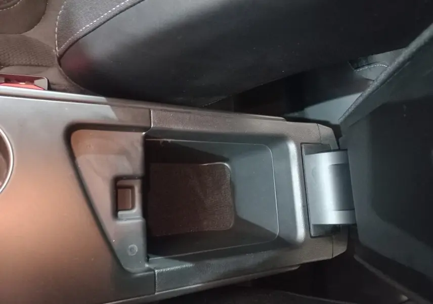 Gros plan sur le rangement central ouvert de la Renault Mégane Business TCe 115 gris foncé, intérieur noir.