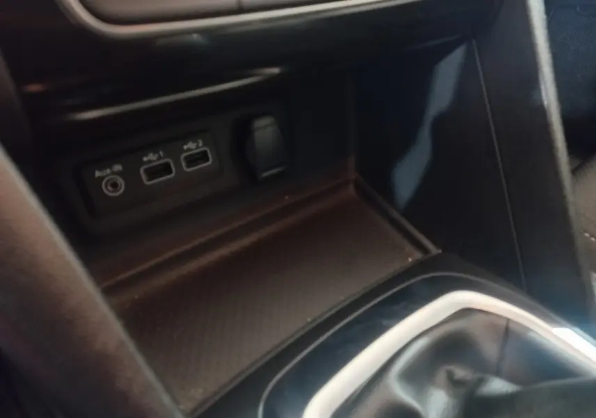 Gros plan sur la console centrale intérieure de la Renault Mégane Business gris foncé, avec ports USB et prise auxiliaire visibles.