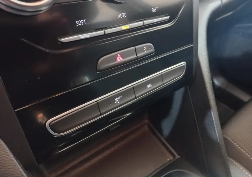Gros plan sur la console centrale noire de la Renault Mégane Business TCe 115, montrant les boutons de sécurité et climatisation.