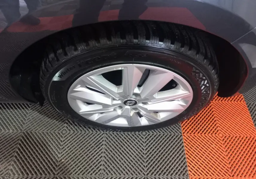 Gros plan sur la roue avant droite d’une Renault Mégane Business gris foncé, jante alliage argentée visible.