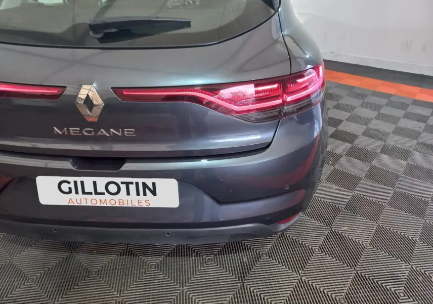 Vue arrière de la Renault Mégane gris foncé, mettant en valeur les feux LED et le logo central sur un sol damier.
