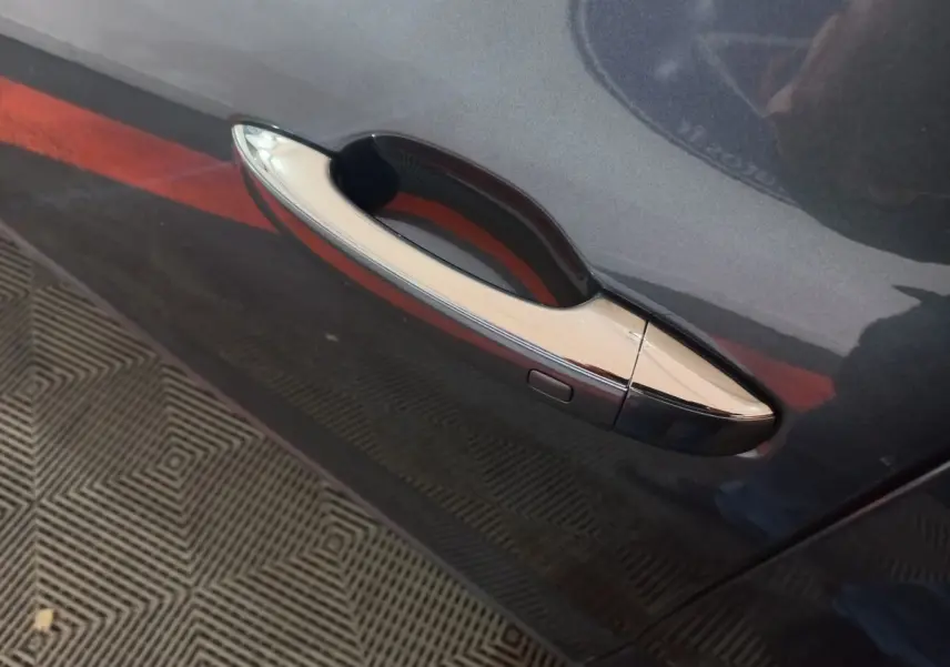 Poignée de porte chromée sur la portière côté gauche d'une Renault Mégane Business gris foncé vue en gros plan.